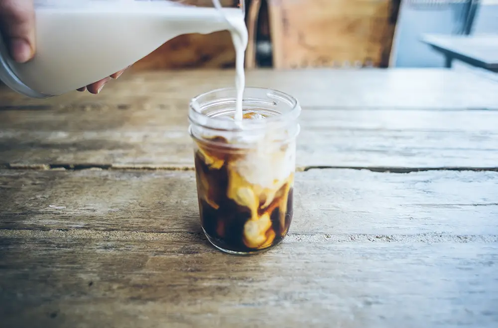 Creamer-pouring-into-coffee-wood-background