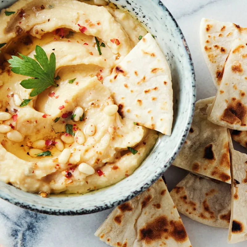 Huisgemaakte hummus met pijnboompitten en pitabroodjes